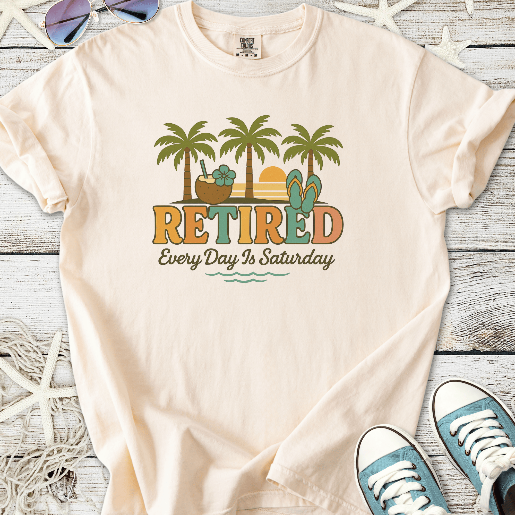 Light peach retired graphic tee with palm trees, flip flops, and beach elements for relaxed summer vibes.