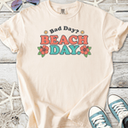 Cream cotton t-shirt with 'Bad Day? BEACH DAY.' graphic and floral designs.