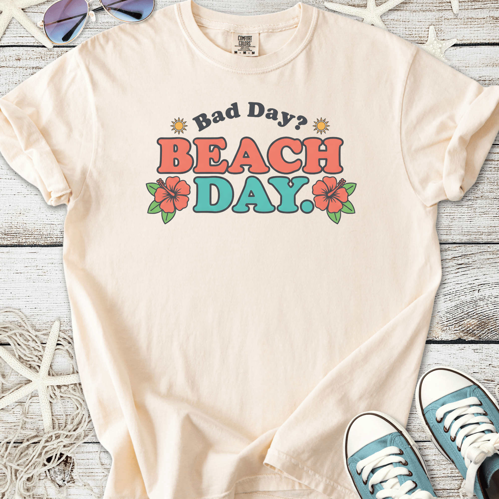 Cream cotton t-shirt with 'Bad Day? BEACH DAY.' graphic and floral designs.