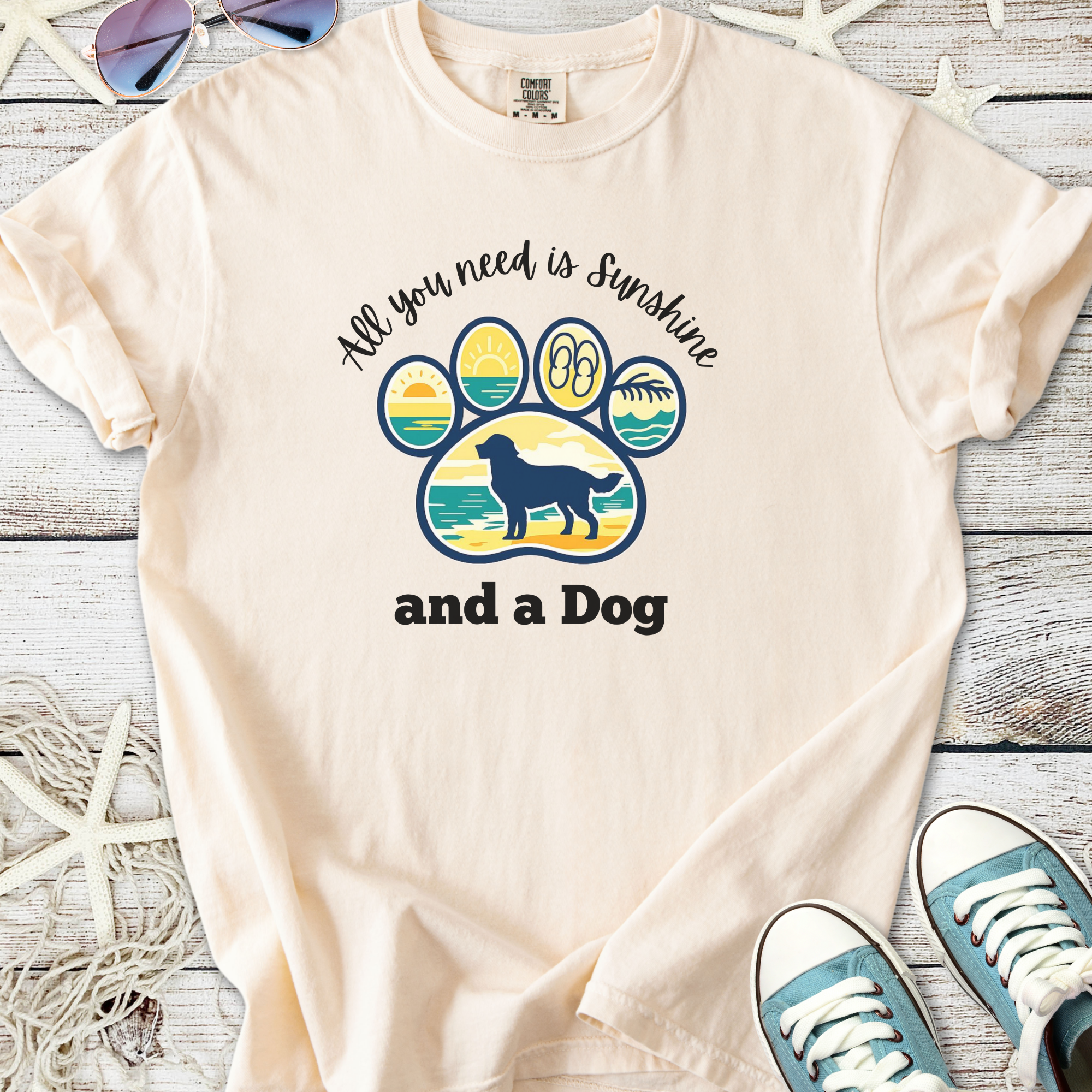 Cream graphic tee featuring a playful dog paw print and the phrase, 'All you need is Sunshine and a Dog'.