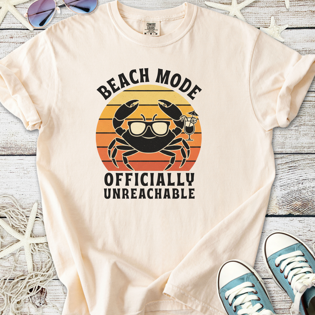 Cream beach-themed t-shirt featuring a crab graphic with sunglasses, stating 'Beach Mode - Officially Unreachable'.
