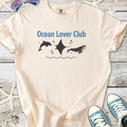 Light peach t-shirt featuring 'Ocean Lover Club' graphic with dolphins and manta ray design.
