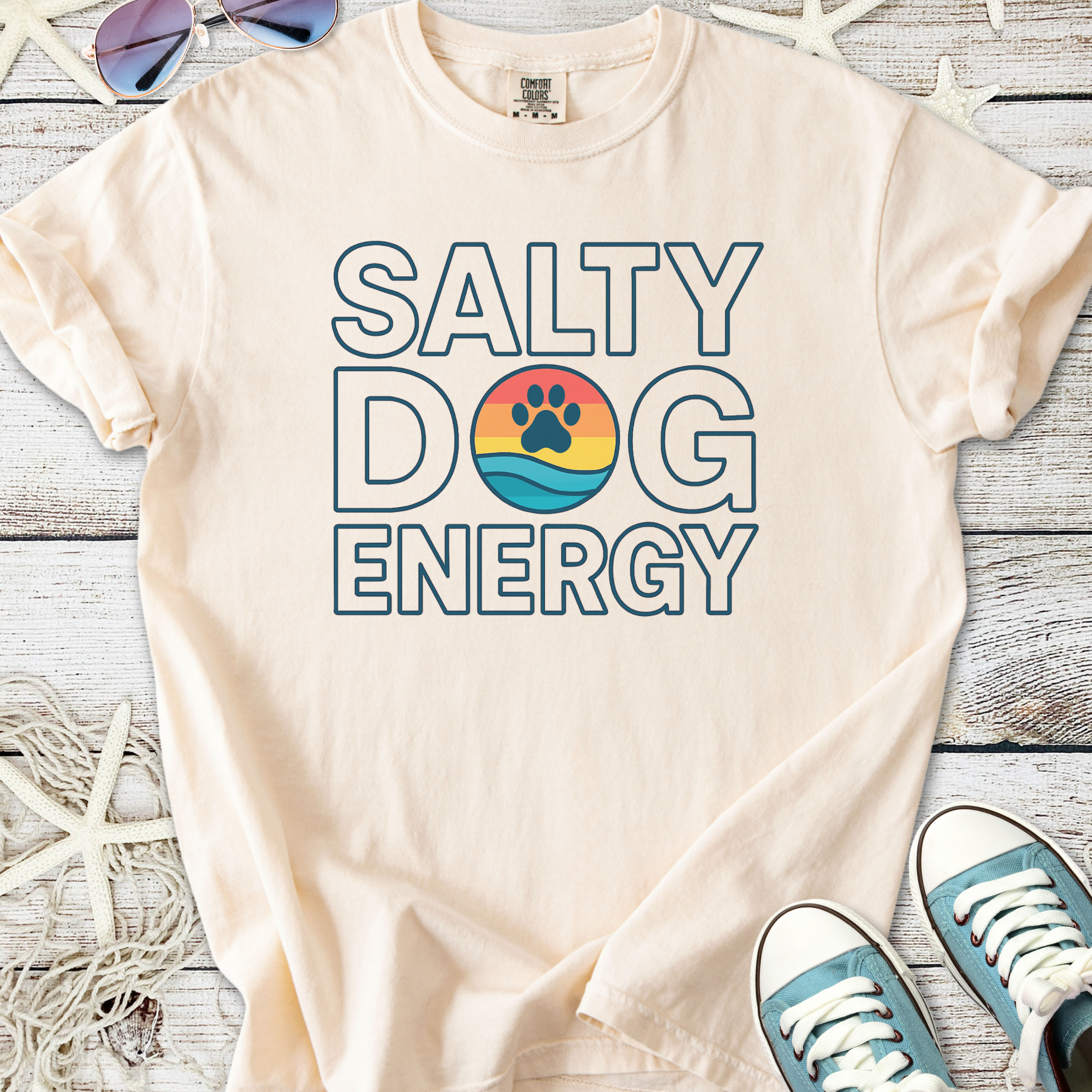 Cream t-shirt with 'Salty Dog Energy' graphic, featuring a beach scene and paw print design.