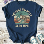Navy blue t-shirt featuring a sloth graphic, text 'Current Velocity Zero MPH', casual cotton material.