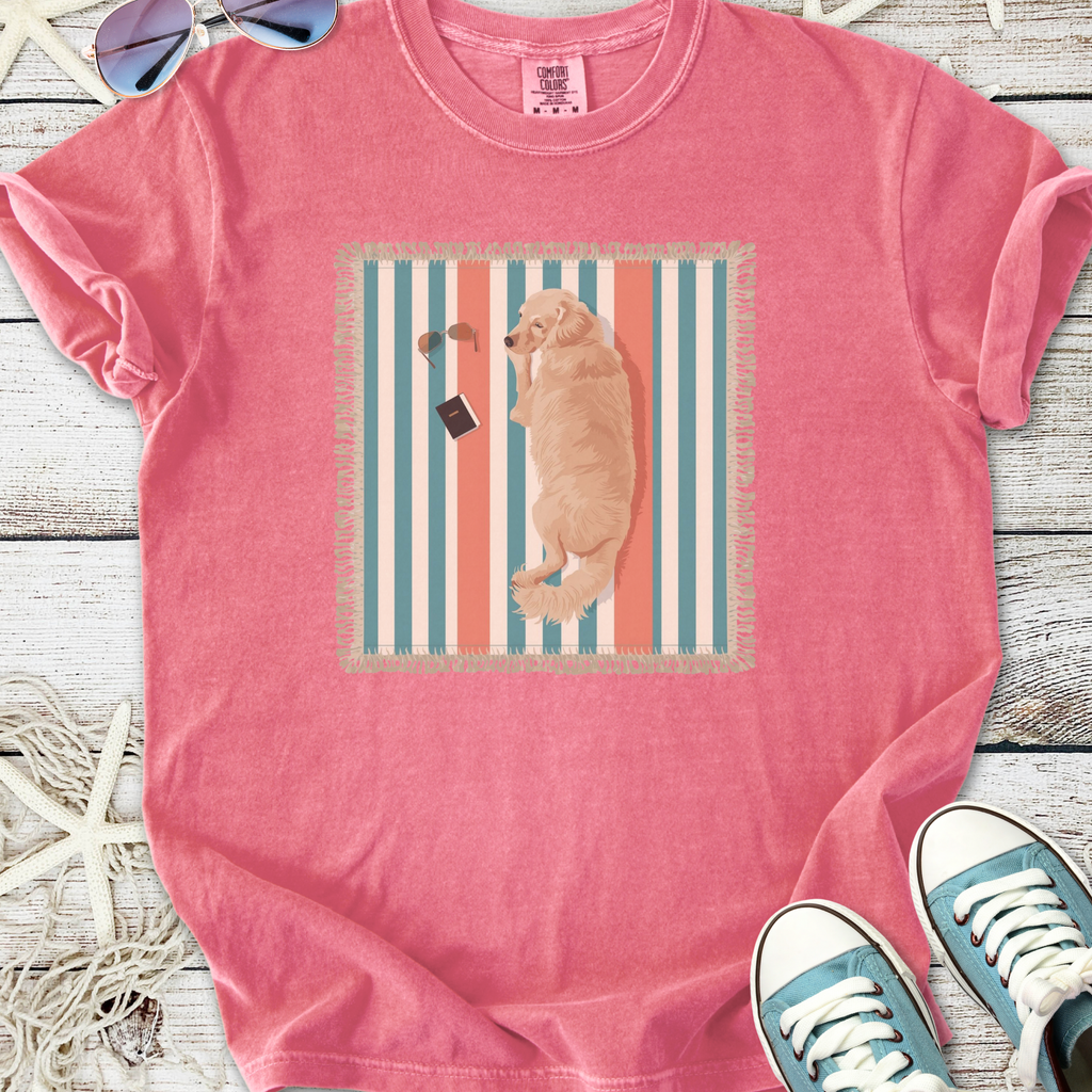 Pink graphic T-shirt featuring a golden retriever lounging on a beach towel with sunglasses and a book.