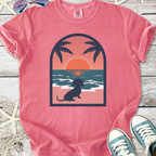 Pink graphic tee featuring a dog silhouette, sunset, and palm trees, perfect for casual beach vibes.